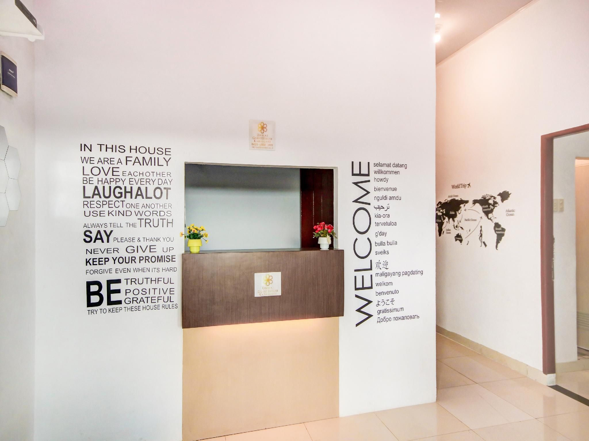 A hotel reception area with a welcome sign and a list of house rules on the wall.