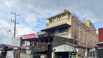 A multi-story building with commercial establishments on the ground floor, including a visible ATM and a sign for a laundry service.
