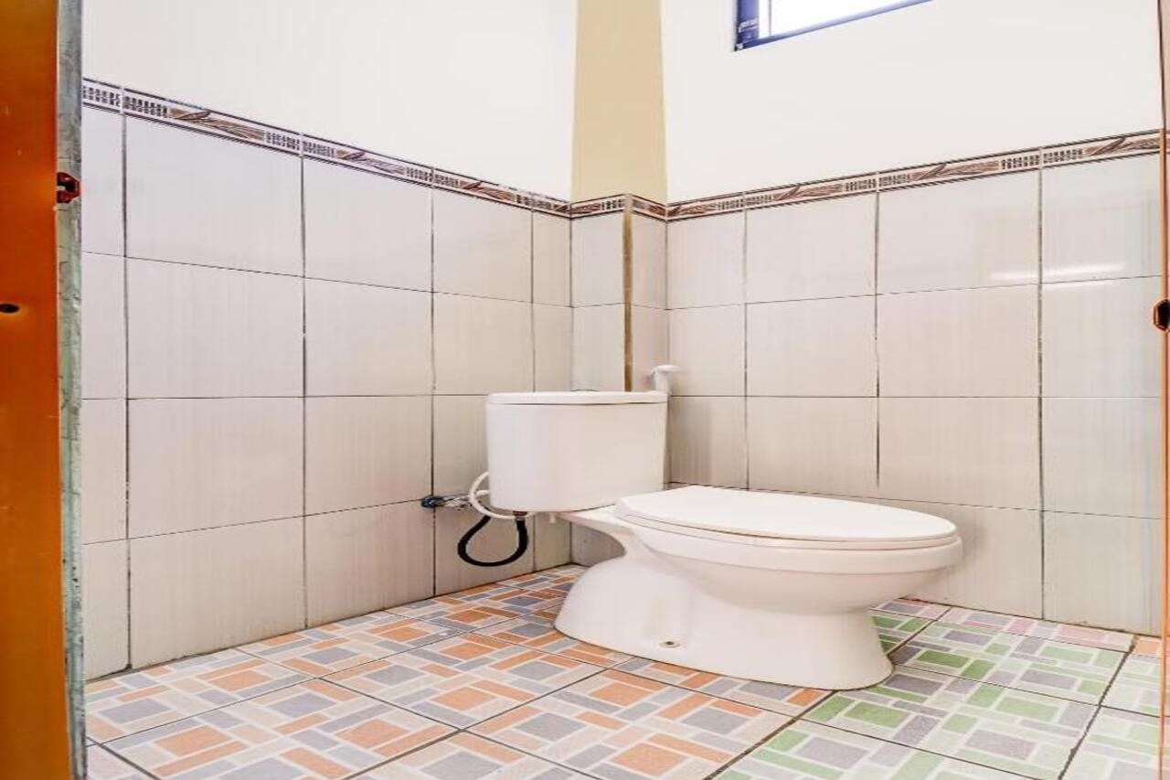 A small bathroom with a toilet, tiled walls, and a patterned floor.