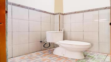 A small bathroom with a toilet, tiled walls, and a patterned floor.