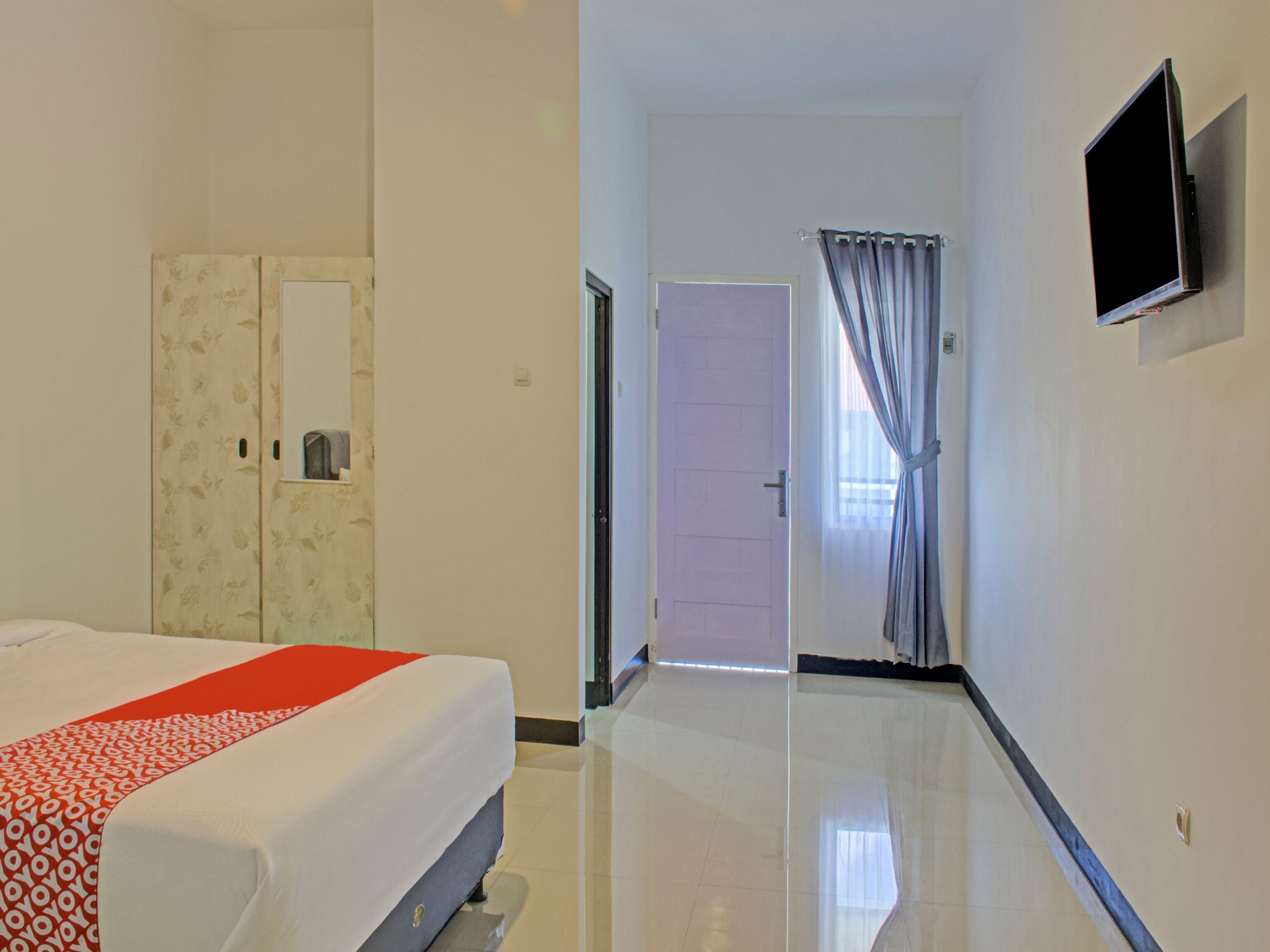 Une chambre d’hôtel comprenant un lit, une armoire, un téléviseur et une porte donnant sur une autre pièce.