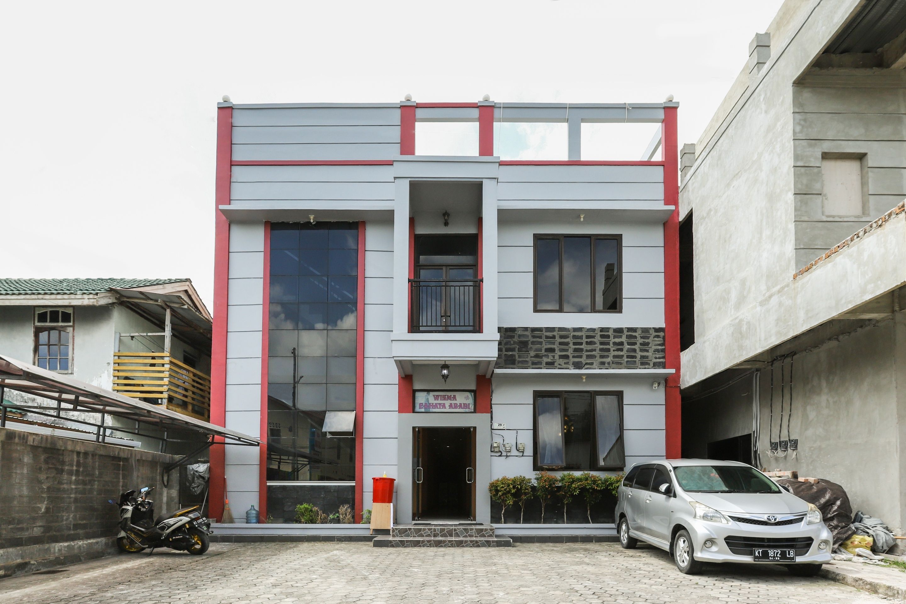 A two-story building with a flat facade, large windows, and a red and grey color scheme.