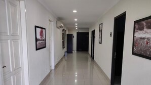 Un passadís amb parets blanques, quadres emmarcados i portes que donen a diferents habitacions.