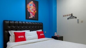 Un llit amb un capçal negre, dos almoinos blancs i dos almoinos vermells amb el logotip 'OYO'.