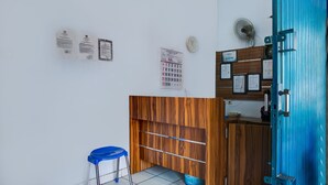 A room with a wooden desk, a blue stool, a calendar, and a blue door. - OYO 3755 Sweet Home (Jakarta)