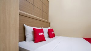 A bed with white bedding and two red pillows with the text "OYO" on them. - OYO 3755 Sweet Home (Jakarta)