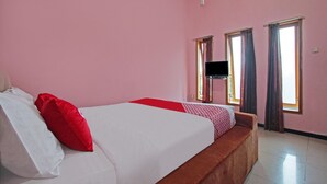 A hotel room with a large bed, a TV, and two windows with curtains. - OYO 3866 Villa Gothick (Batu)