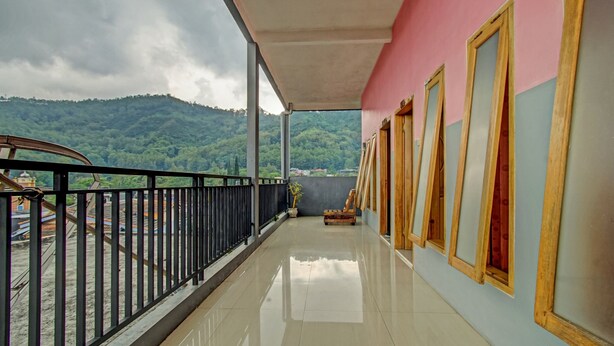 A balcony with a view of green hills, a tiled floor, and a railing. - OYO 3866 Villa Gothick (Batu)