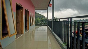 A corridor with a tiled floor, wooden doors, and a balcony with a metal railing. - OYO 3866 Villa Gothick (Batu)