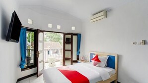 Ein Hotelzimmer mit Bett, Fernseher, Fenster mit Vorhängen und Klimaanlage.