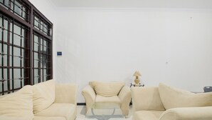 Ein Zimmer mit zwei beigefarbenen Sofas, einem Glastisch und einer Lampe.