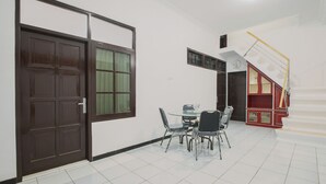 Ein Zimmer mit Esstisch und Stühlen, einer Treppe mit roter Geländer und einer Tür mit Fenster.