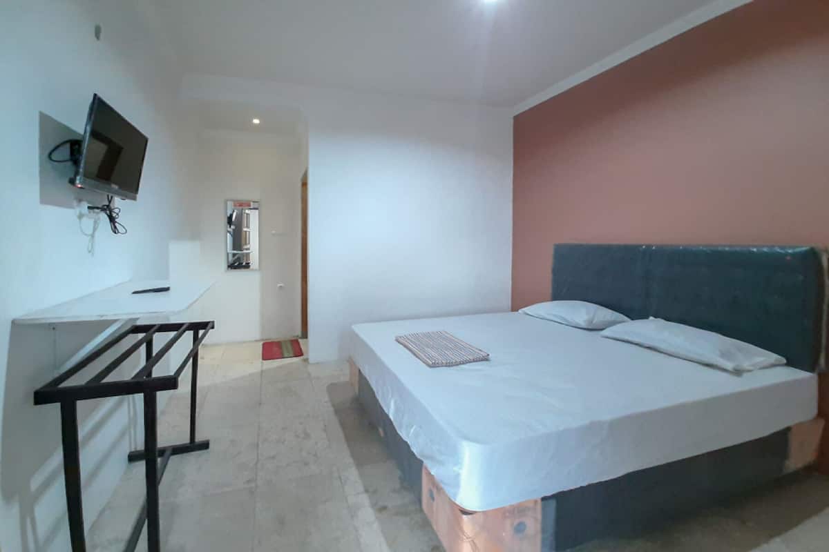 A bedroom with a bed, a desk, and a television.