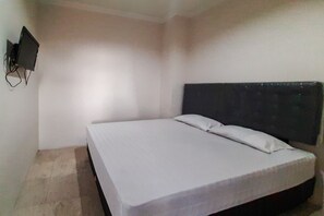 A simple room with a bed, a wall-mounted TV, and a tiled floor. - Rejeki Homestay Syariah Malioboro Redpartner (Yogyakarta)