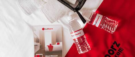 A promotional display with a RedDoorz brochure, a black mesh bag, and a water bottle on a white fabric background.