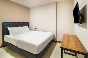A hotel room with a bed, a wooden side table, a flat-screen TV mounted on the wall, and a small bedside table. - Collection O Kebon Jeruk Near Paskal 23 (Bandung)