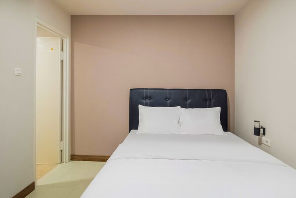 A hotel room with a bed, a door, and a wall-mounted light fixture. - Collection O Kebon Jeruk Near Paskal 23 (Bandung)