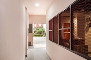 A hallway with a view of a street outside, a window with a mesh screen, and a door leading to an outdoor area. - Collection O Kebon Jeruk Near Paskal 23 (Bandung)