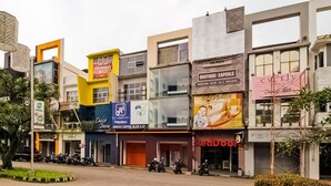 Vista de carrer amb diversos edificis comercials, incloent un centre de serveis, un hotel càpsula de luxe i una botiga RedDoor.