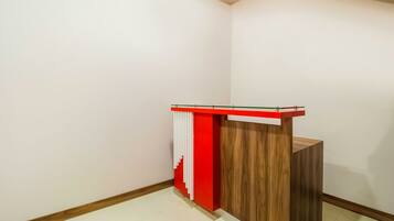 A corner room with a wooden reception desk and a red accent wall.