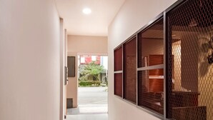 Un passadís amb vista al carrer, una finestra amb mosquitera i una porta que dona a una zona exterior.