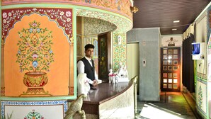 A reception area with a marble counter, a receptionist, and a door labeled "Chamberlain." - Mahal Rajwada Resort (Jaipur)