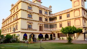 A large, multi-story building with traditional architecture, featuring multiple balconies and arched doorways. - Mahal Rajwada Resort (Jaipur)