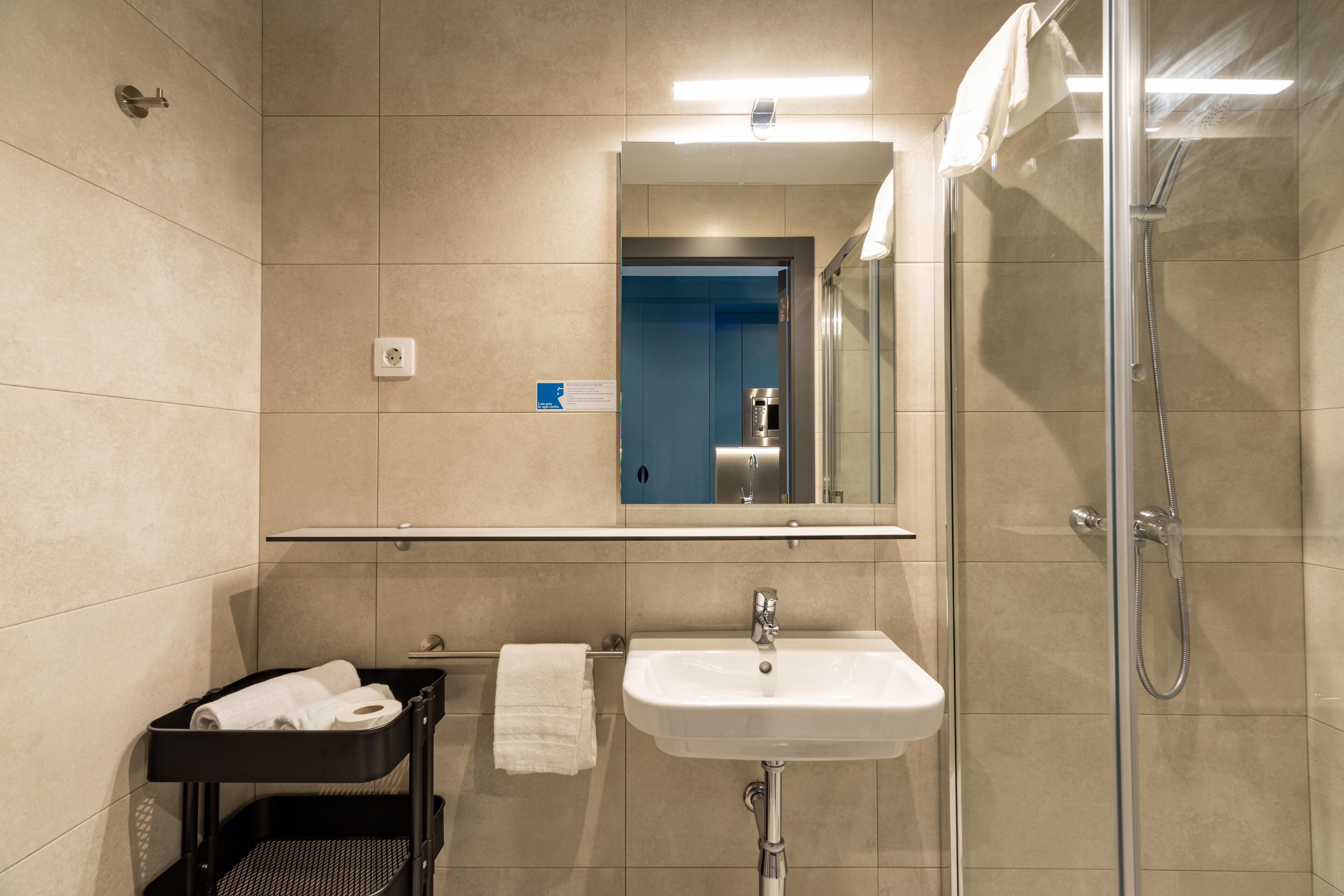 Un baño moderno con lavamanos, espejo y ducha.