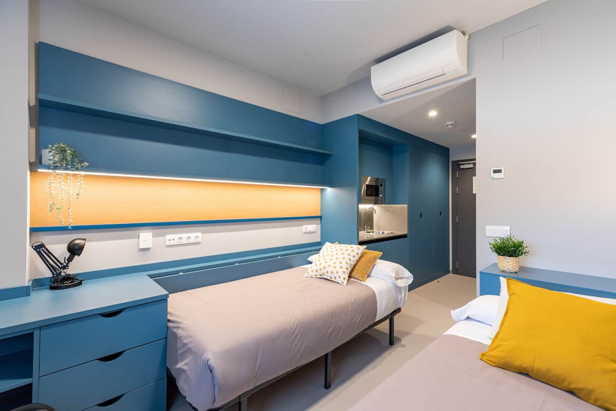 Een moderne slaapkamer met een bed, nachtkastje en een ingebouwde werkplek met een lamp.