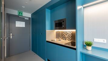 Een moderne keuken met blauwe kastjes, een roestvrijstalen spoelbak, een magnetron en een kleine potplant.