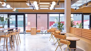 A modern interior with a seating area, tables, and a large window offering a view outside. - Residencia Universitaria Resa San Mamés - Campus Accomodation (Bilbao)