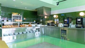 Una cucina moderna con piastrelle verdi, piani di lavoro in acciaio inossidabile e diversi prodotti alimentari esposti.