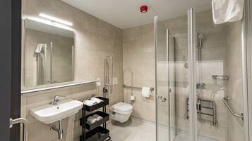 A modern bathroom with a glass shower enclosure, a sink with a towel rack, and a toilet with a grab bar.