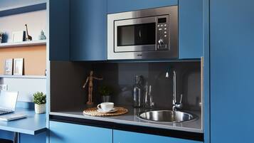 A modern kitchen with a built-in microwave, stainless steel sink, and a laptop on the counter.
