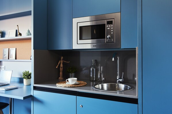 A modern kitchen with a built-in microwave, stainless steel sink, and a laptop on the counter. - Residencia Universitaria Resa San Mamés - Campus Accomodation (Bilbao)