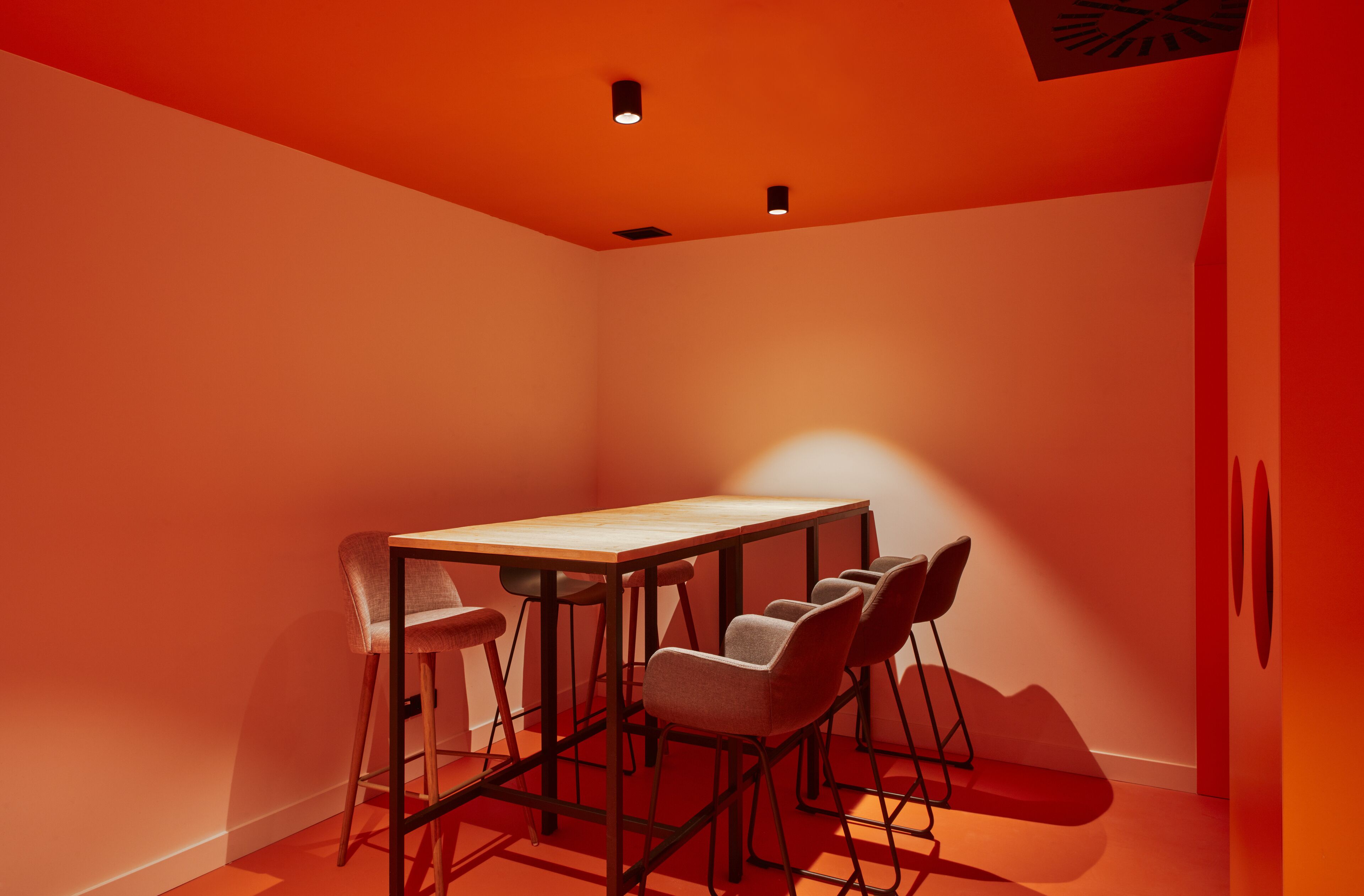 A conference room with a rectangular table and six chairs, illuminated by ceiling lights.