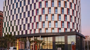 Un edificio moderno con fachada a cuadros, un paso de peatones y una señal de estacionamiento.
