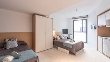 Una habitación de hotel moderna con dos camas, un armario, un escritorio y un ventanal grande.