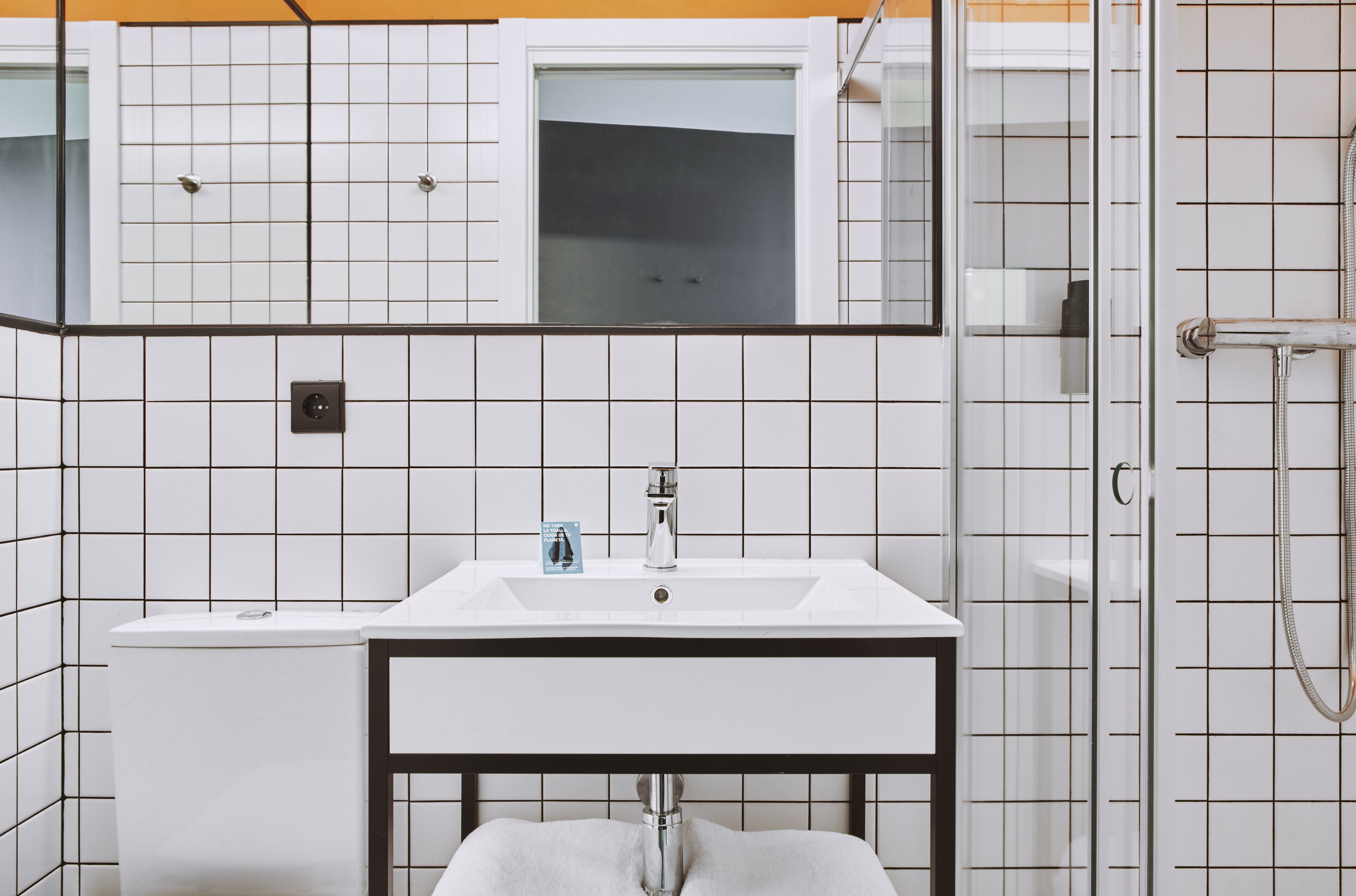 Un baño con lavamanos blanco, espejo y ducha.