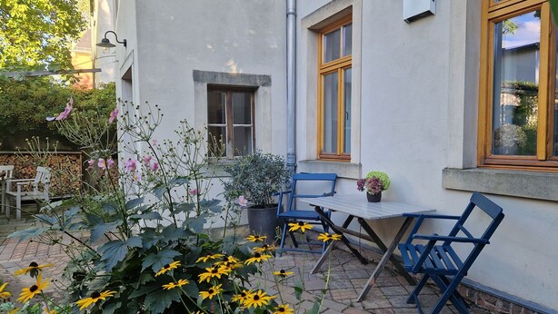 A patio with a table and chairs, surrounded by plants and flowers. - Stylishly furnished apartment in Dresden including bicycles, close to the center (Dresden)