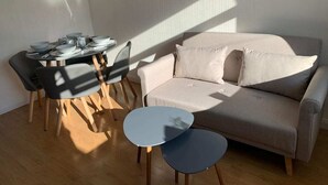 Uma sala de estar moderna com um sofá, uma mesa de jantar com cadeiras e uma pequena mesa de centro.