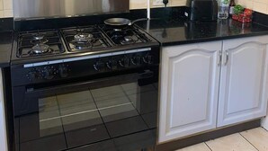 Uma cozinha com fogão preto, armários brancos e painel de azulejos.