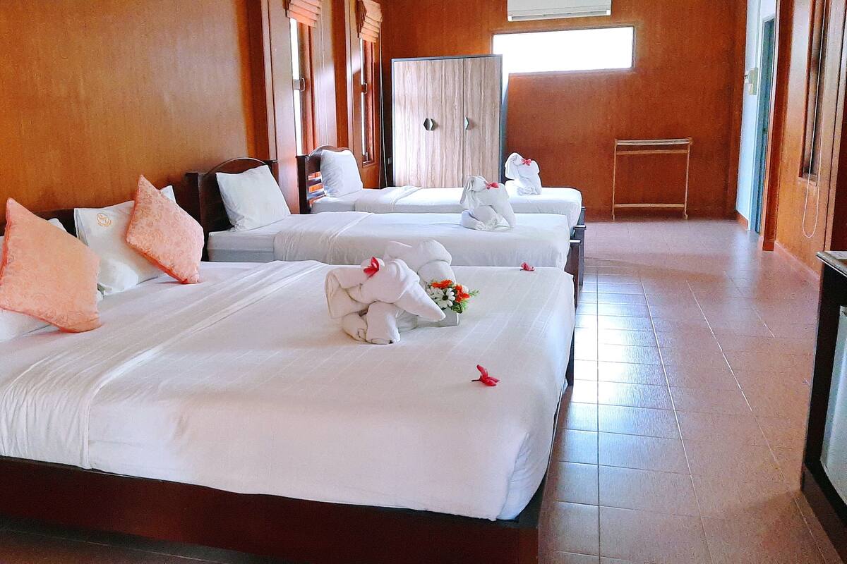 A hotel room with three neatly made beds, each with white linens and decorative pillows.