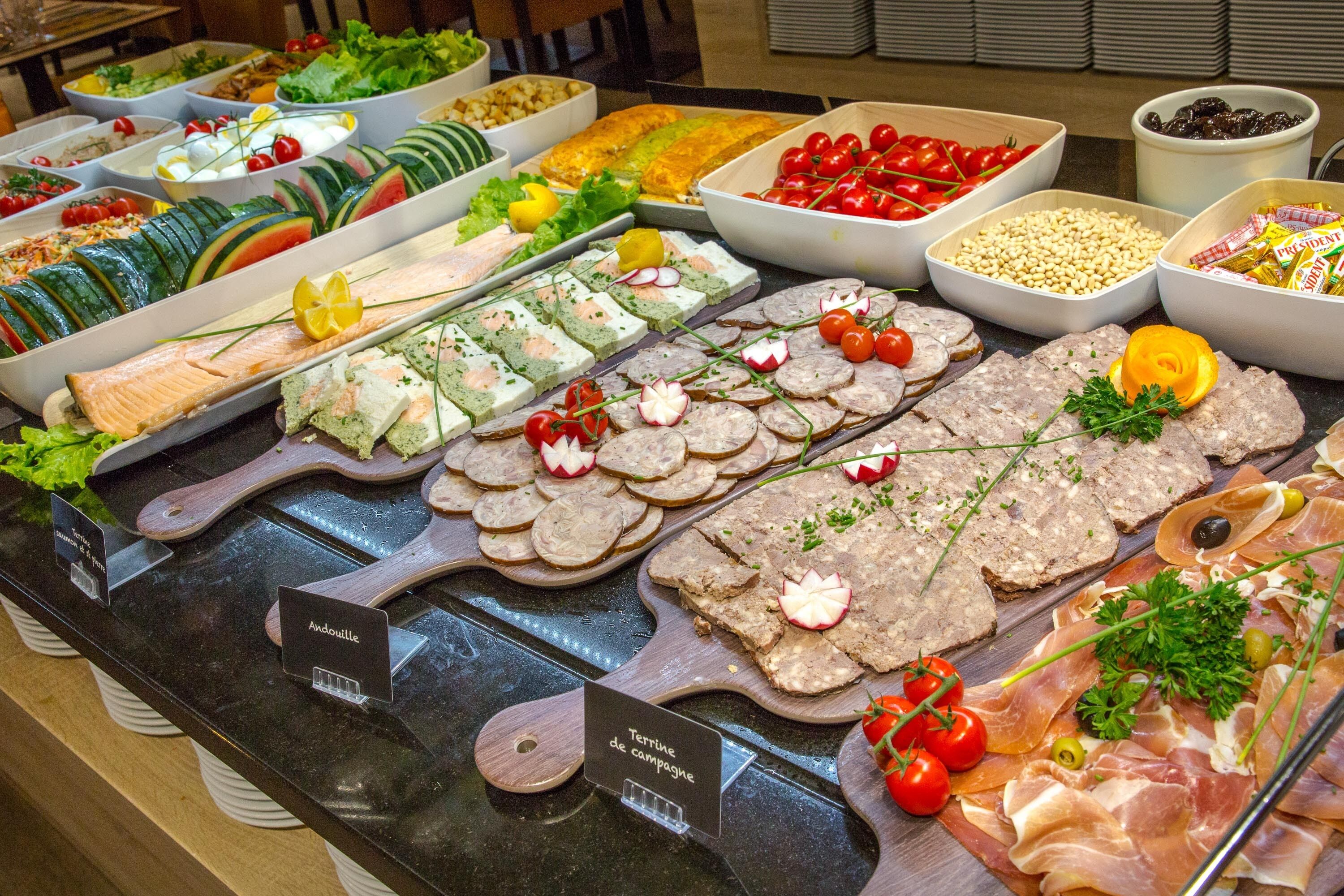 Un bufé con diversas opciones de comida, incluyendo carnes, quesos y ensaladas.
