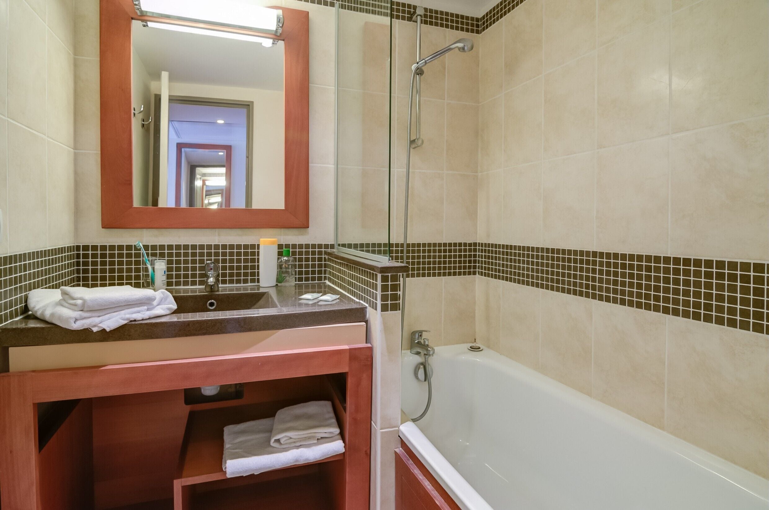 A bathroom with a bathtub, a sink with a mirror, and a shower.