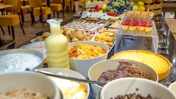 Ein Buffet mit verschiedenen Speisen, darunter Obst, Desserts und Getränke.