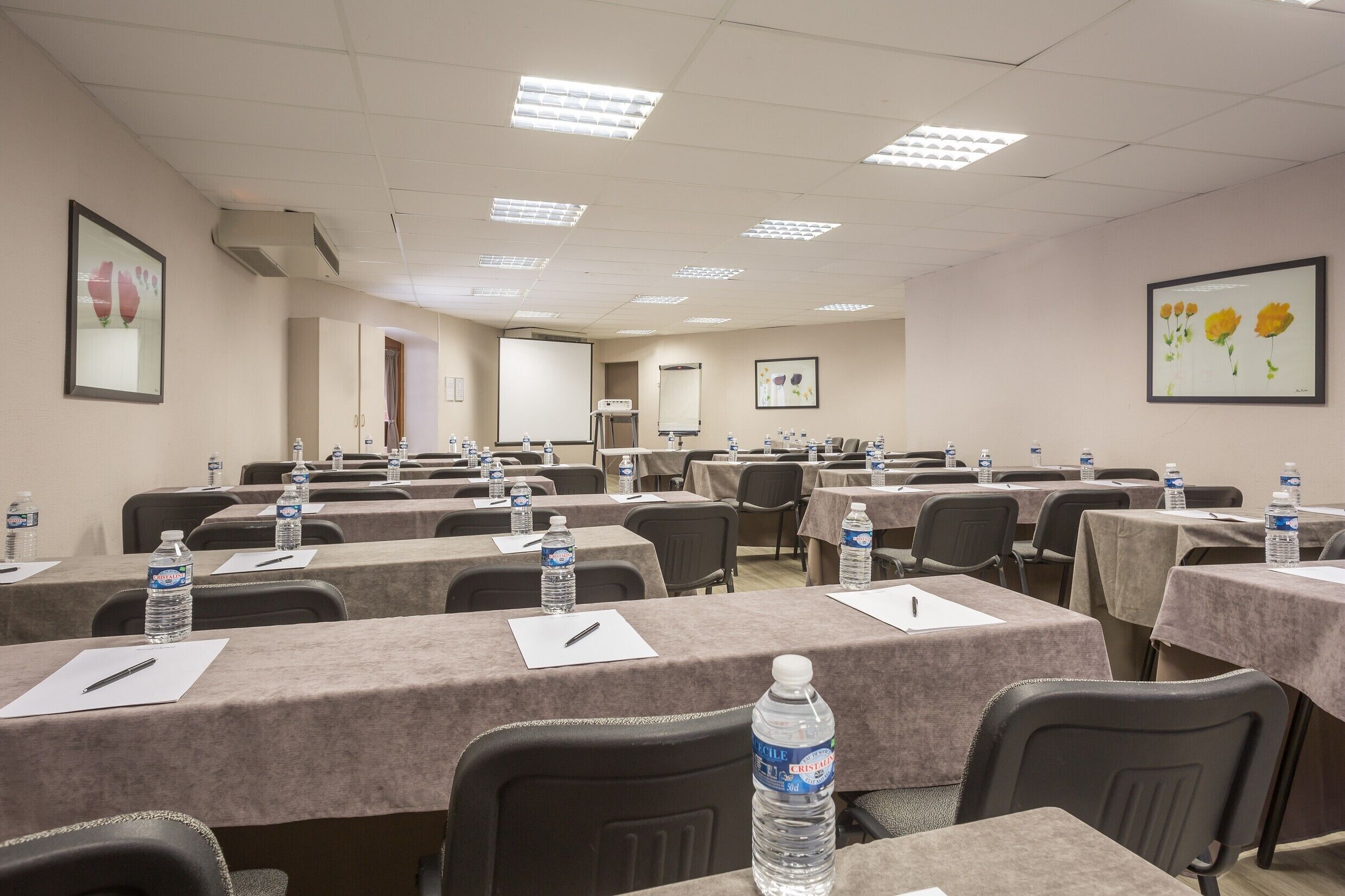 A conference room with tables set up for meetings, equipped with water bottles and pens.