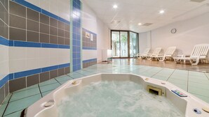 Un espace bien-être comprenant un jacuzzi, des murs carrelés et des chaises longues.