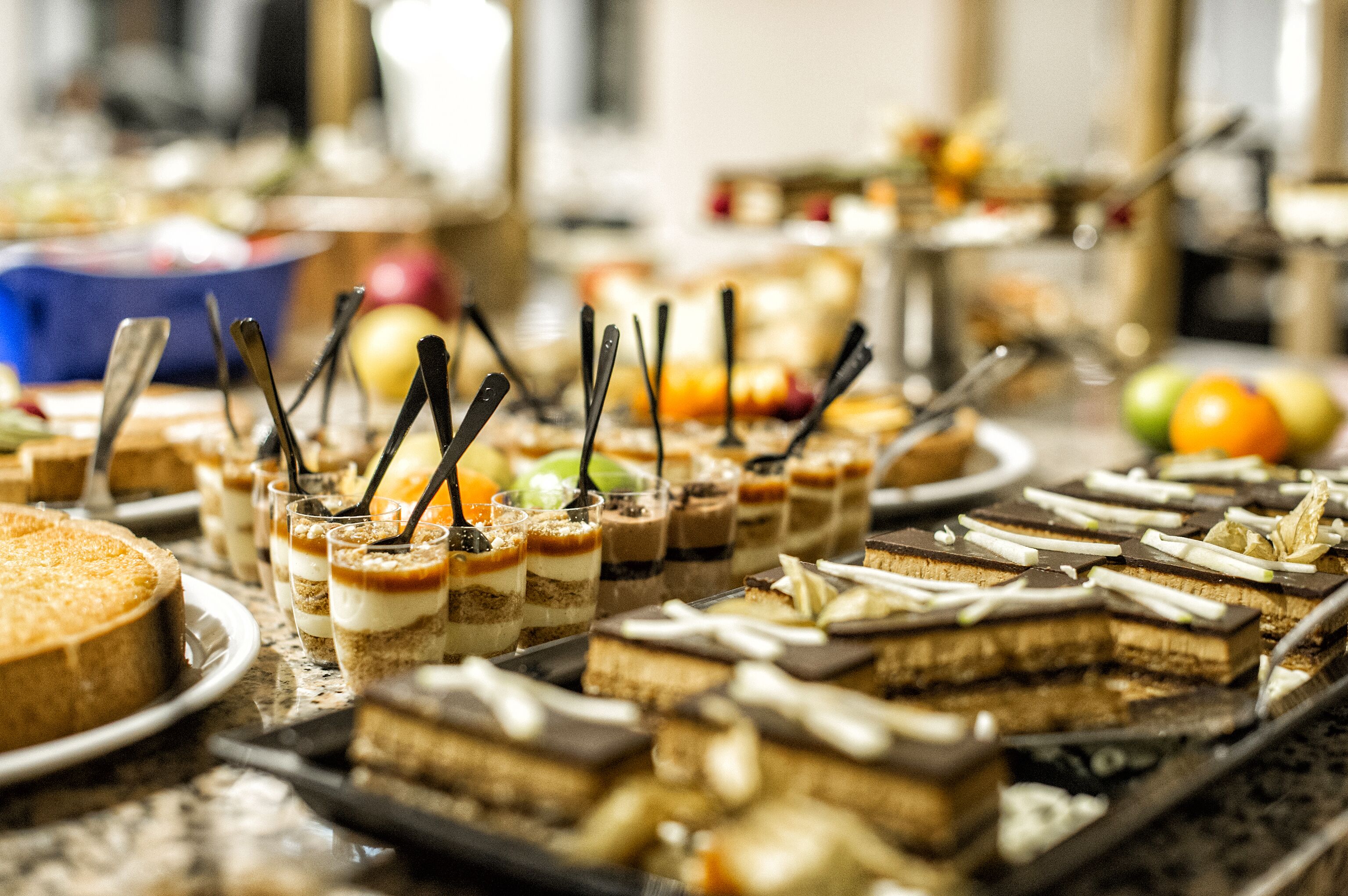 Diverse desserts op een buffet, waaronder taarten met lagen en parfaits.