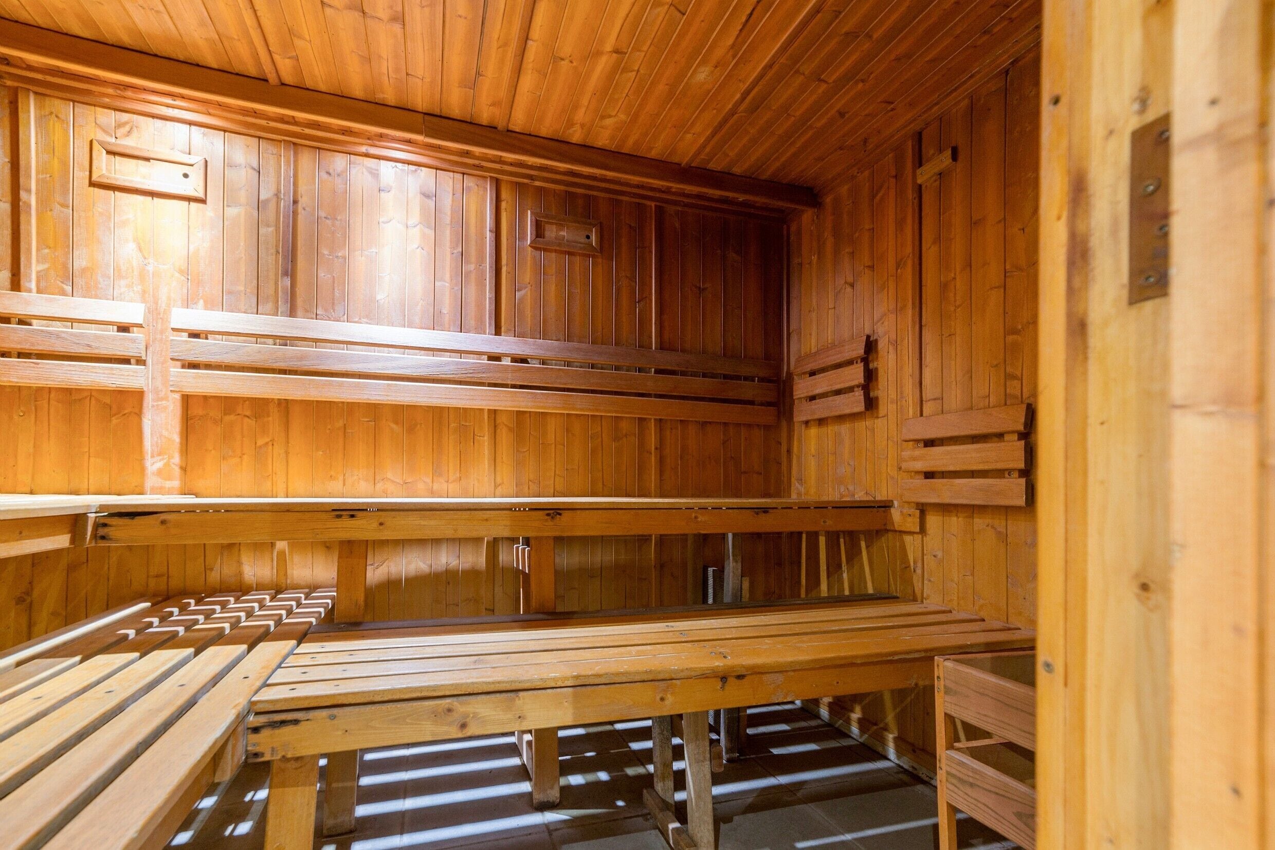 A sauna with wooden benches and walls, featuring a sloped ceiling and a central bench.